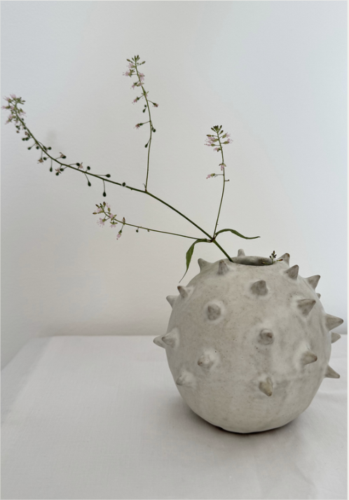 A round ceramic bud vase covered in hand-applied spikes